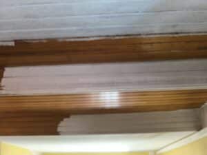 Plafond en bois clair partiellement peint en blanc, révélant le bois brun d'origine. Rénovation d'un plafond à lattes.